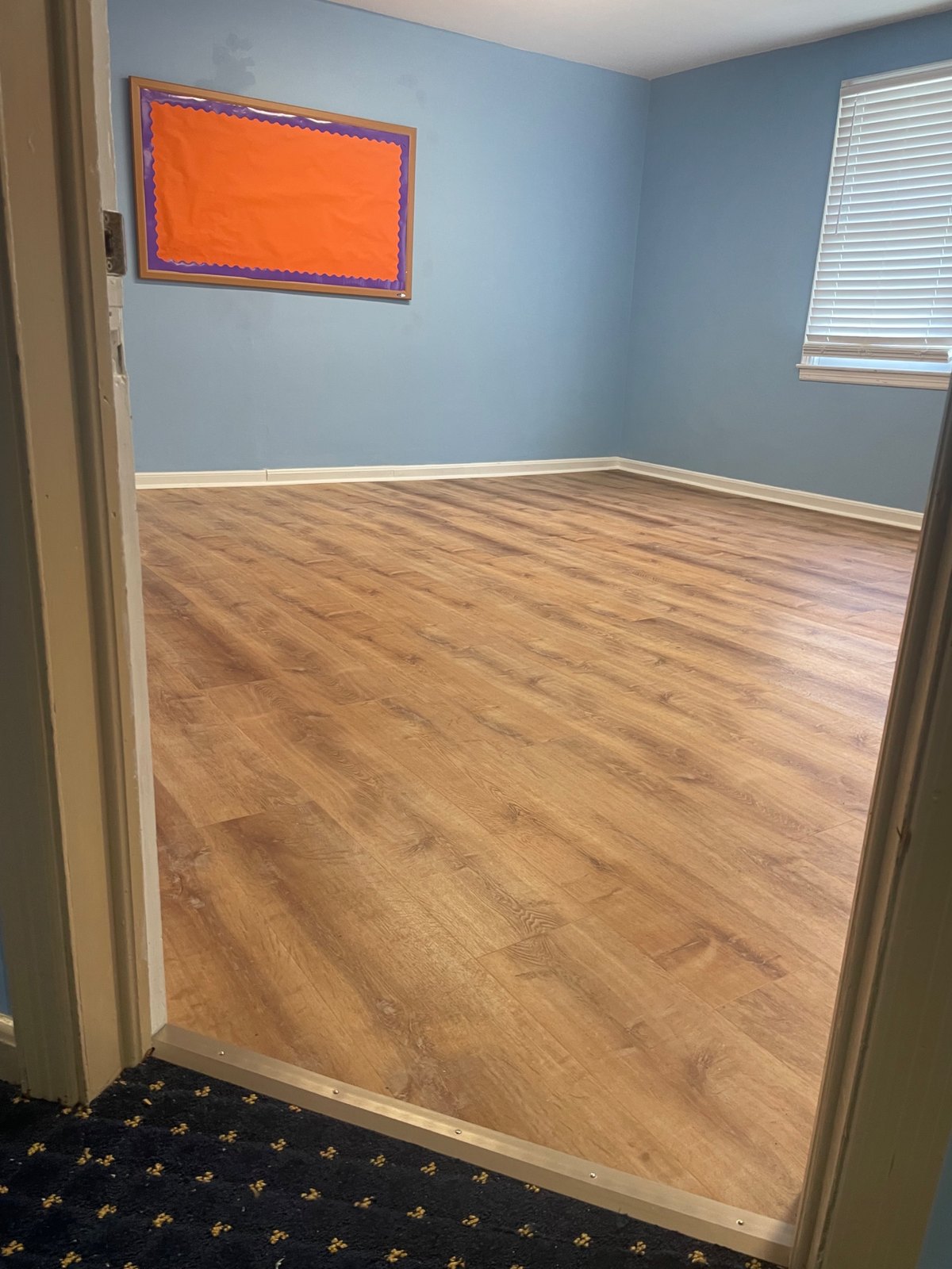 New wood-look vinyl plank flooring in a blue room with a bulletin board